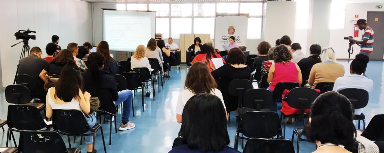 Pessoas sentadas em cadeiras enfileiradas em uma sala