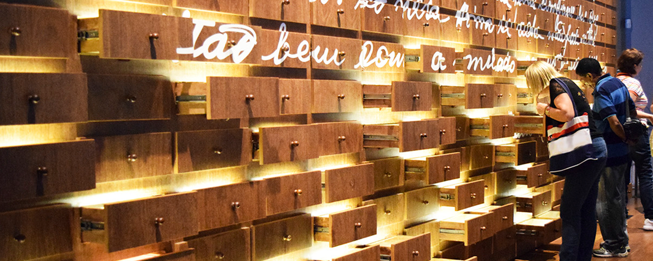 Foto de uma parede de madeira com gavetas e duas pessoas olhando