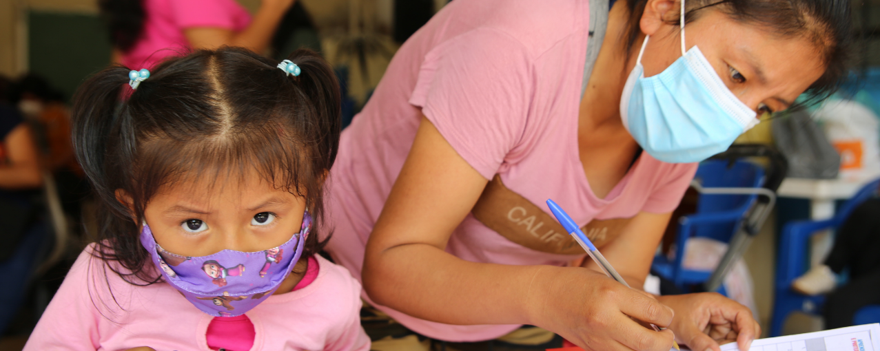 Foto de criança e mulher de máscara.