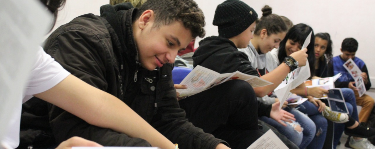 Alunos sentados em fileira com material educativo