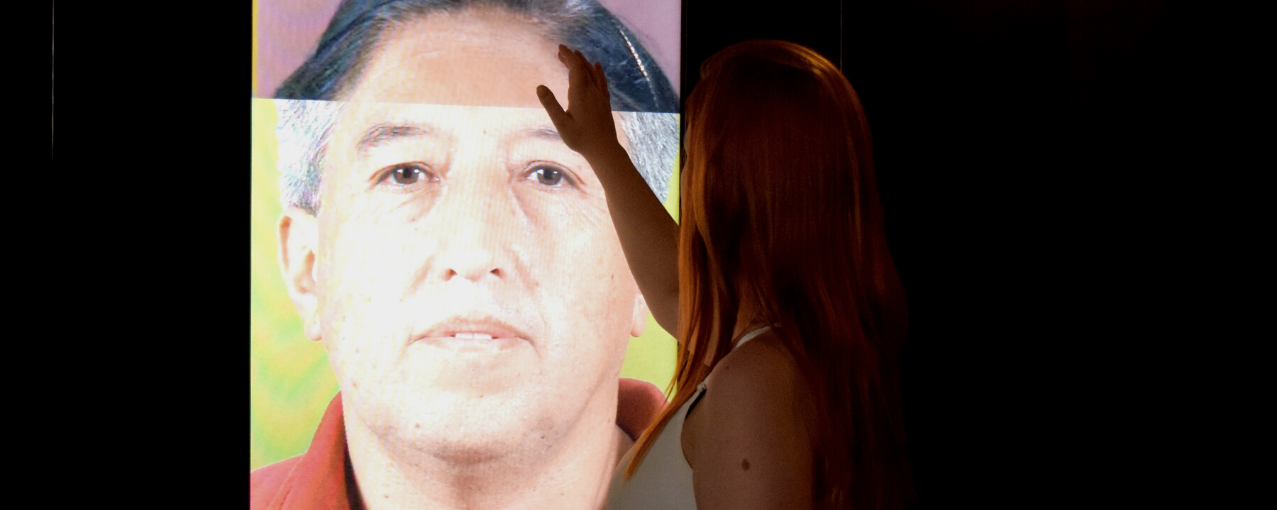 imagem de mulher tocando uma tela na exposição.